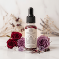 Huile rituelle Féminin Sacré 10 ml dans une fiole en verre avec étiquette illustrée, composée de plantes, fleurs et cristaux pour accompagner les rituels d’amour de soi, d’intuition, de créativité, de transformation intérieure et de force intérieure.